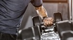Man lifting a heavy single dumbbell off the dumbbell rack