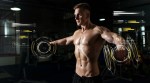 Muscular young bodybuilder training his deltoid muscles using the best delt exercises as he tracks his performance