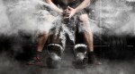 Kettlebells in front of bodybuilder creating a cloud of chaulk by clapping his hands before performing double kettlebell swings
